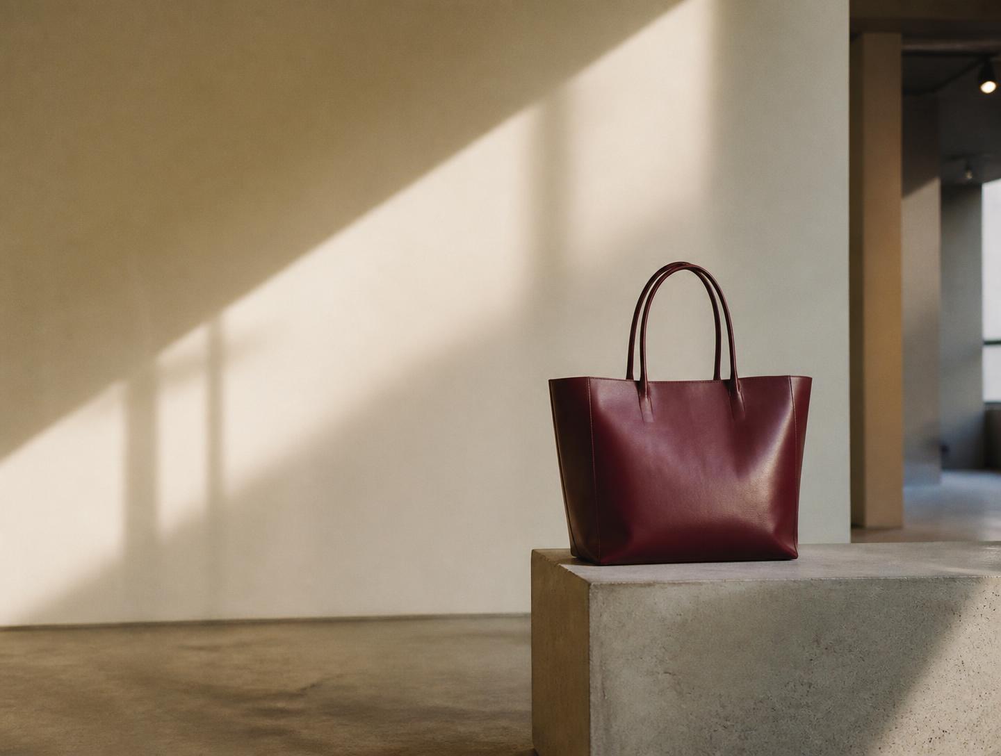 Oxblood leather tote on a concrete plinth in a daylit retail space